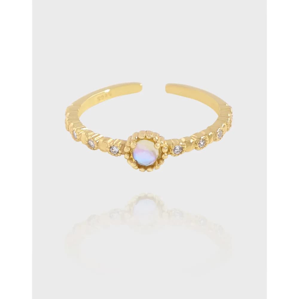 Polished sterling silver ring with an iridescent opal centerpiece and beaded edge on a light background.