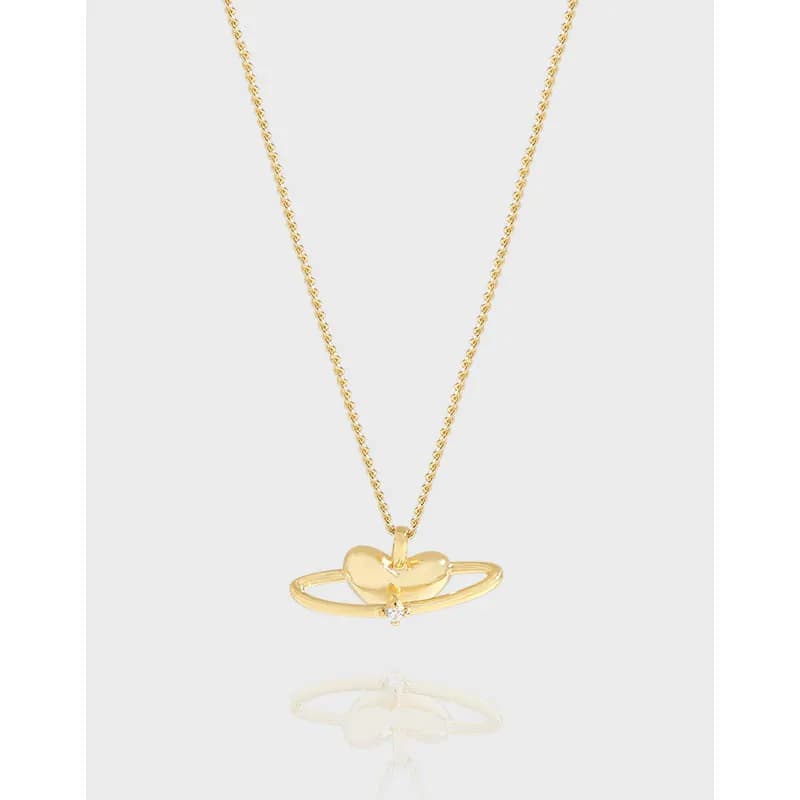 Polished sterling silver necklace with a small heart pendant resting on an open ring and a tiny gemstone.