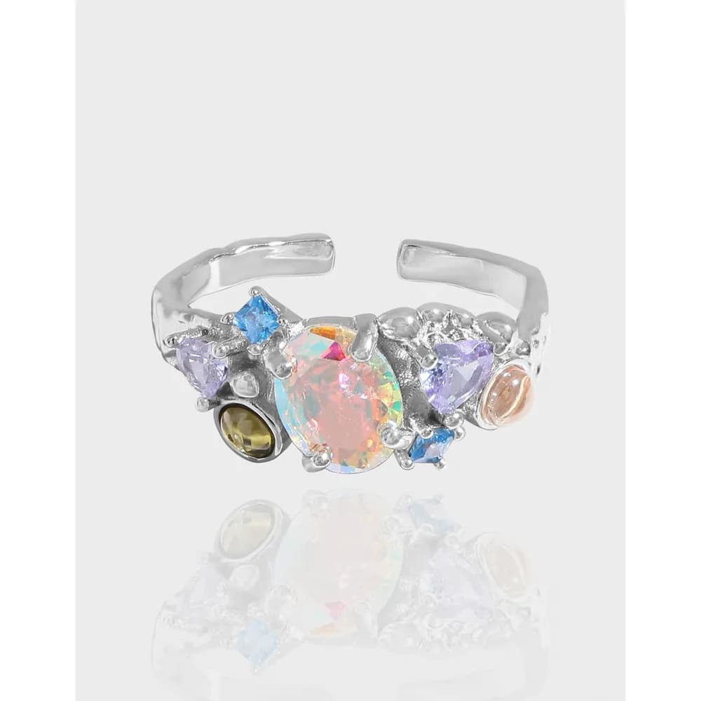 Open adjustable silver ring with a rainbow gemstone cluster including a central opalescent oval stone and surrounding pastel stones.