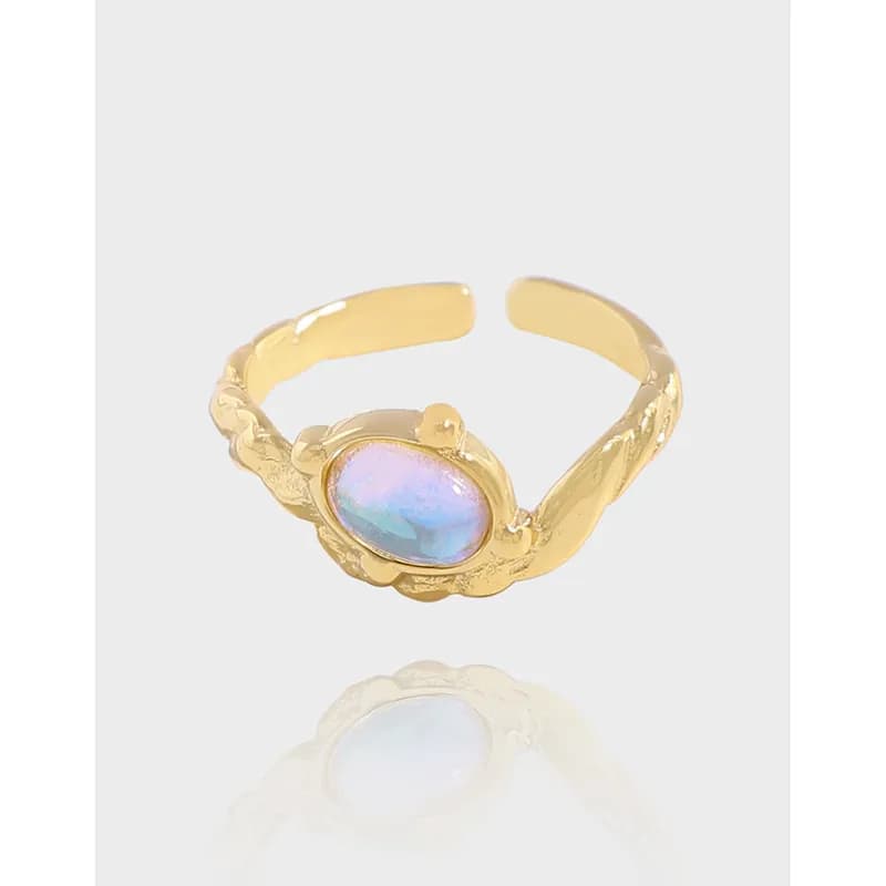 Gold-tone ring with a textured band and oval iridescent stone in a bezel setting.