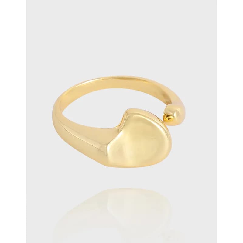 Polished silver-toned open-ended ring with a heart-shaped end on a light background.