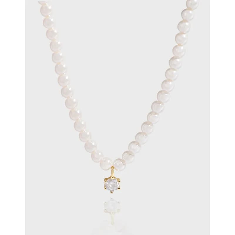 Polished sterling silver pearl necklace with a gold-tone two-tier pendant featuring a round stone and a hanging drop.