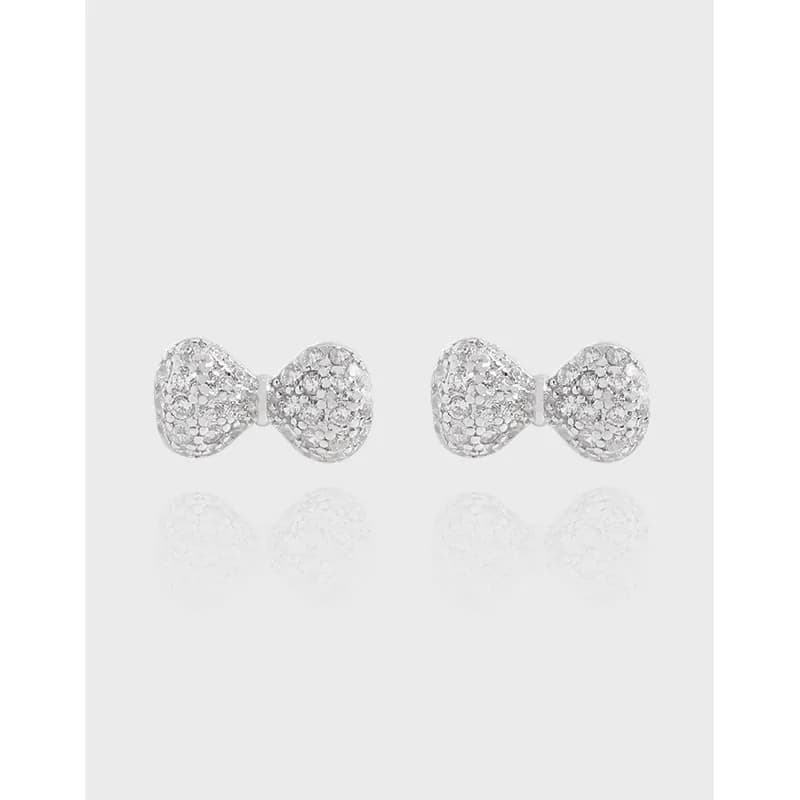 Polished sterling silver pavé bow earrings shown on a light background.