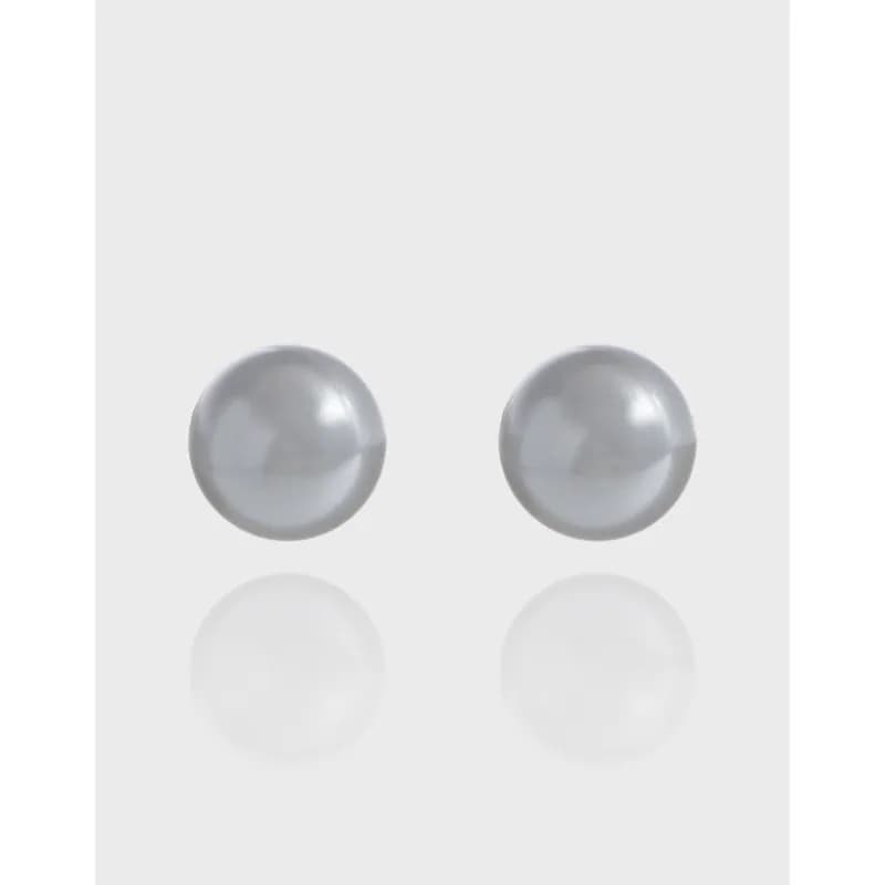Pair of grey pearl stud earrings on a light background with subtle reflection