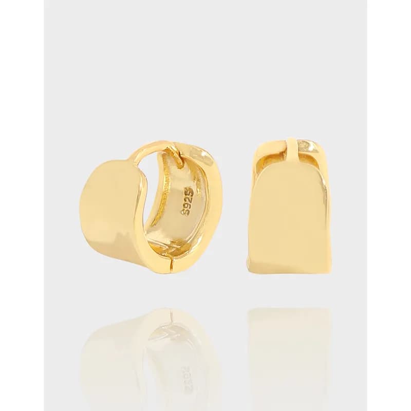 Polished rectangular huggie hoops in sterling silver hanging from the ear