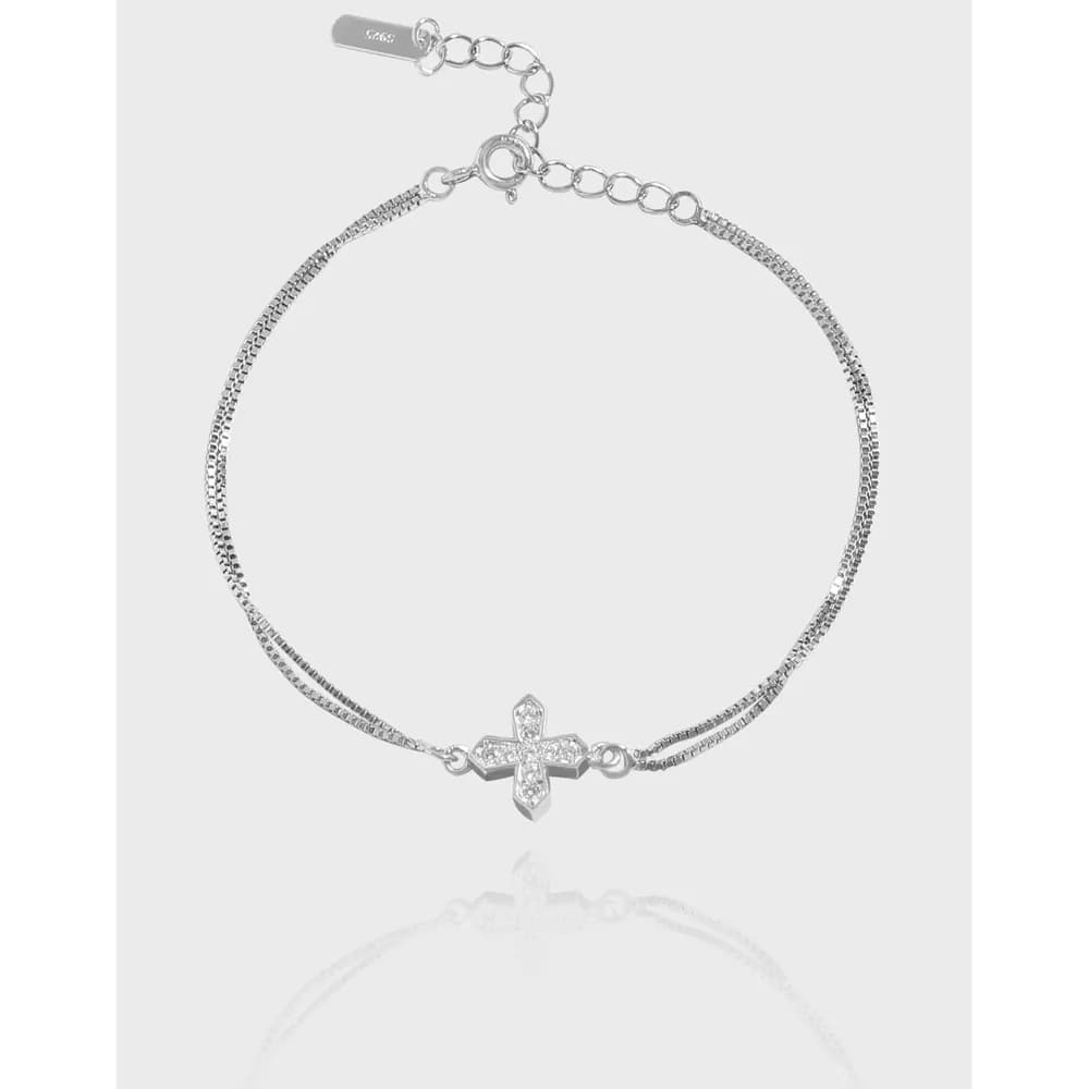 Polished sterling silver bracelet with a pavé cross charm on a clean white background.