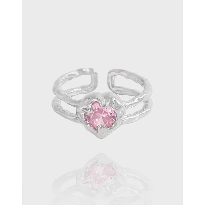 Sterling silver ring with a pink heart-cut gemstone in a scalloped bezel on a pale background.