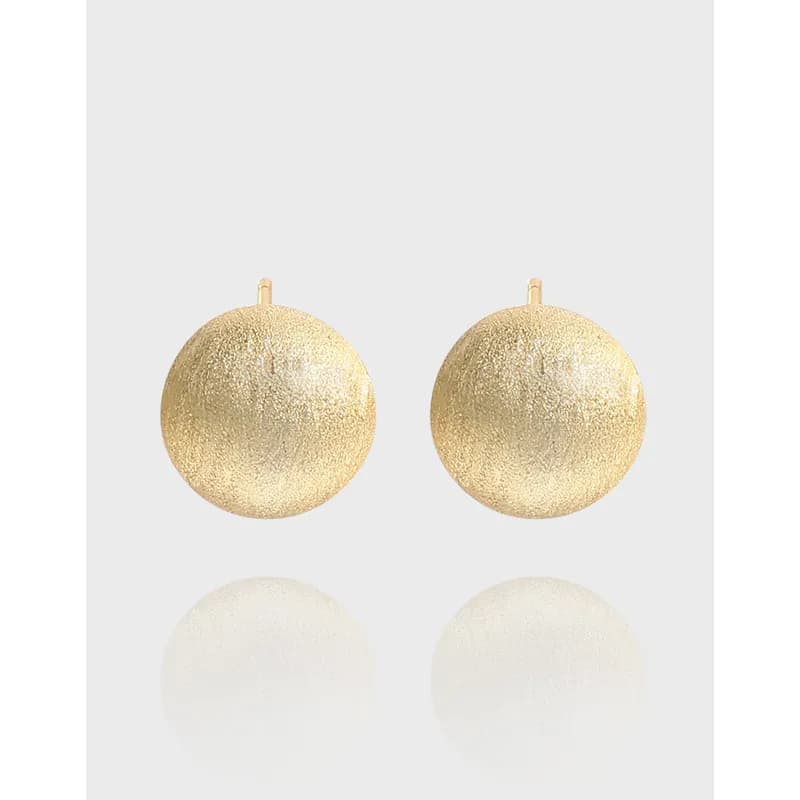 Two round textured disc earrings with posts against a light gray background