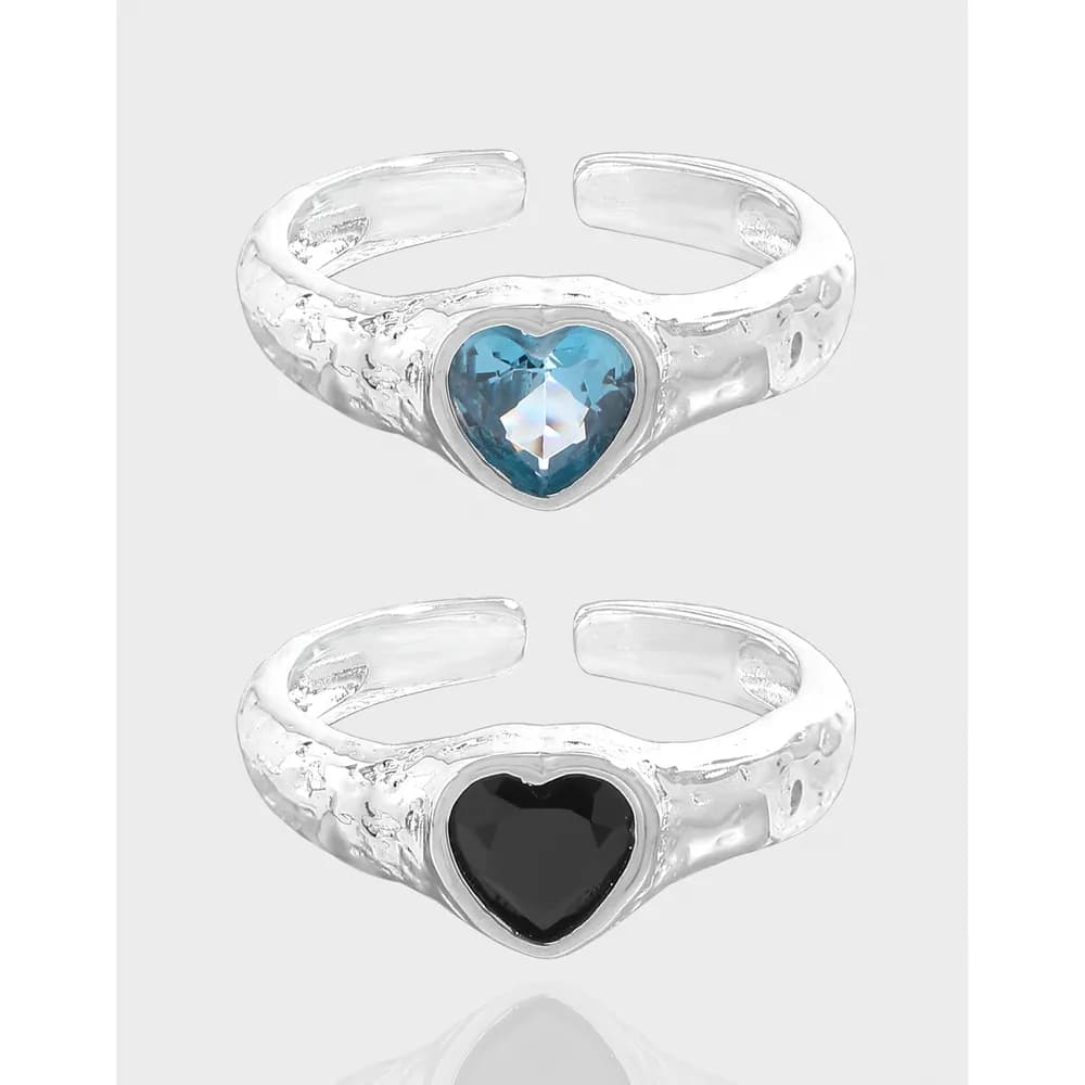 Two sterling silver rings with heart-shaped enamel centers, one blue and one black, displayed side by side.
