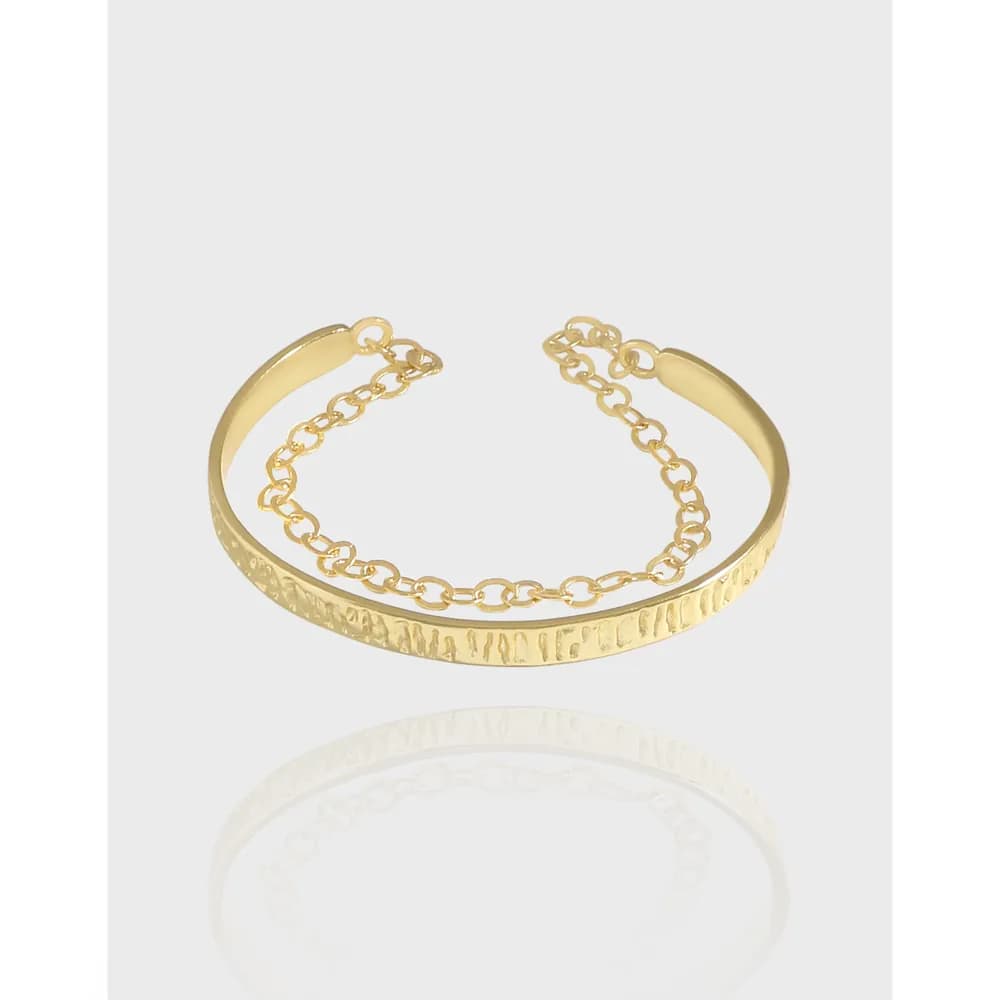 Open-ended polished cuff bracelet in sterling silver with a textured center band and a short linked chain on one side.