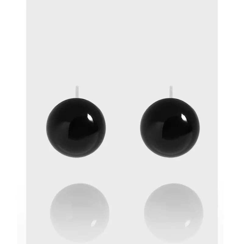 Two glossy black ball stud earrings on silver posts against a pale background.