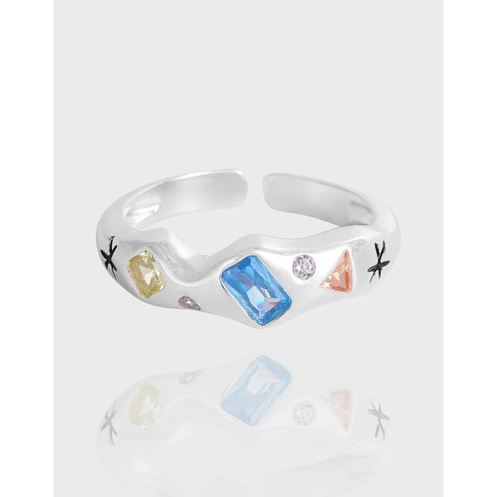 Open silver ring with multicolor gemstones and star engravings on the sides.
