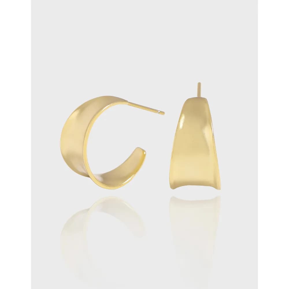 Polished sterling silver geometric earrings: a curved hoop and a tall triangular drop against a white backdrop.
