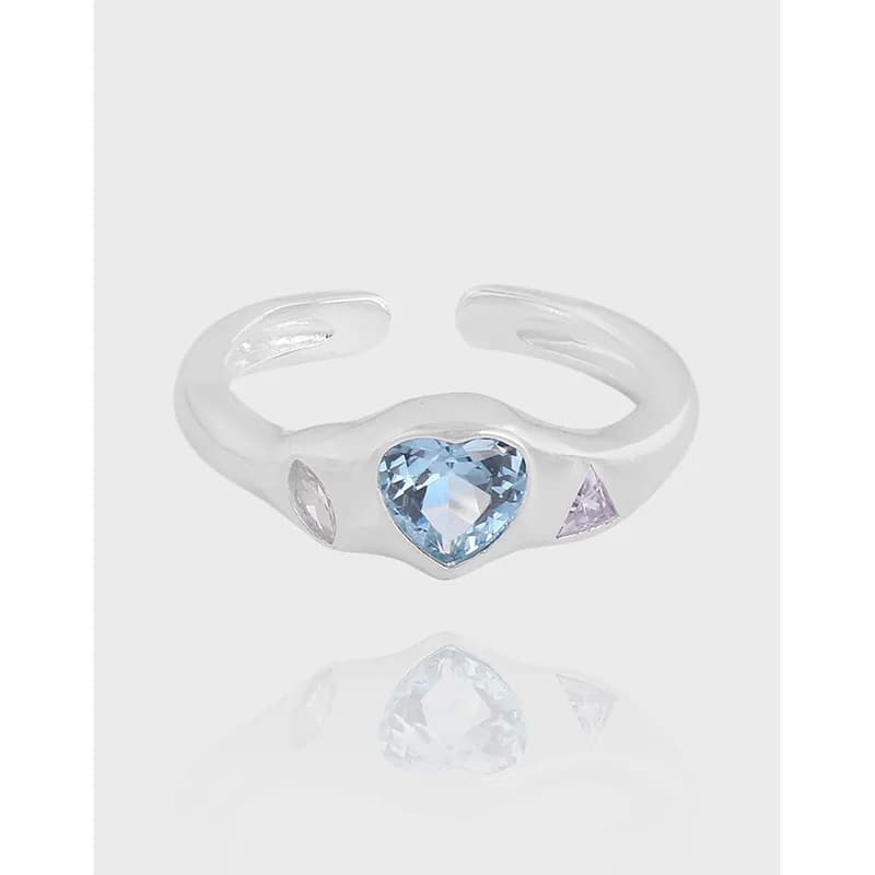 Polished sterling silver open-band ring with a heart-shaped blue gemstone centerpiece and two side stones.