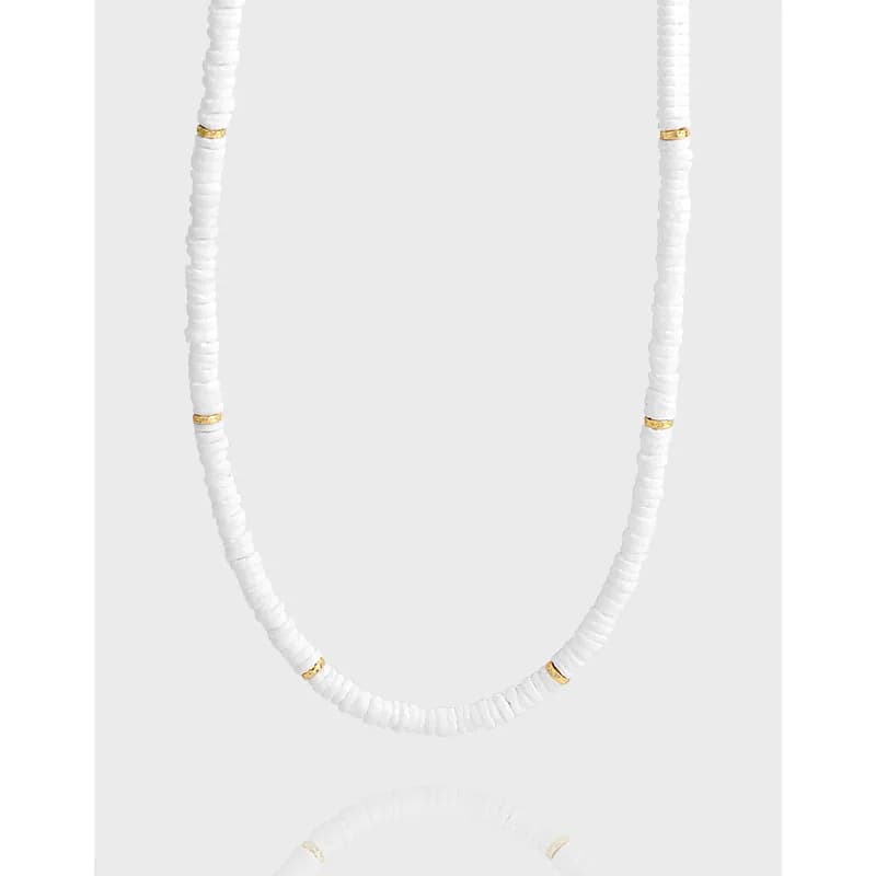 Close-up of a white disc-bead necklace with small gold spacers on a silver chain