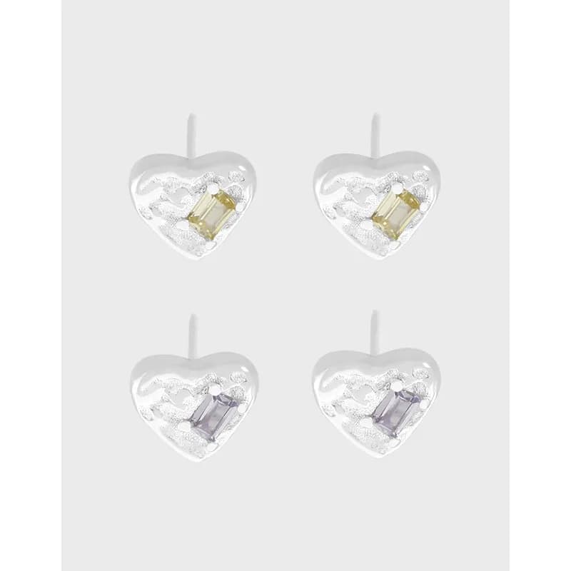 Four polished sterling silver heart-shaped stud earrings, each with a rectangular pale yellow or lavender gem set inside.