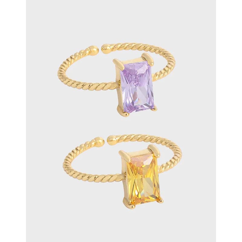 Two open-ended twisted rope rings in sterling silver with rectangular emerald-cut stones in purple and yellow.