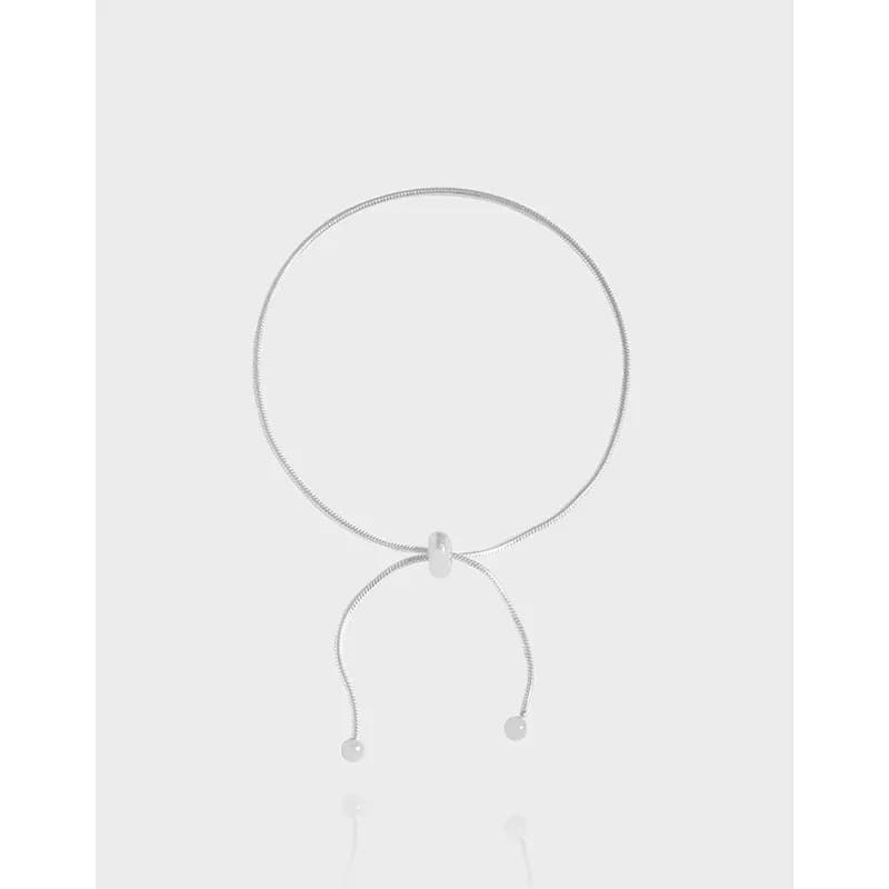 Polished sterling silver circle bracelet with two curved tails and ball-end charms hanging beneath the large loop.