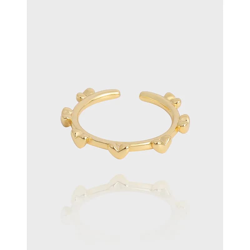 Polished sterling silver ring with heart-shaped accents along the band, resting on a light background.