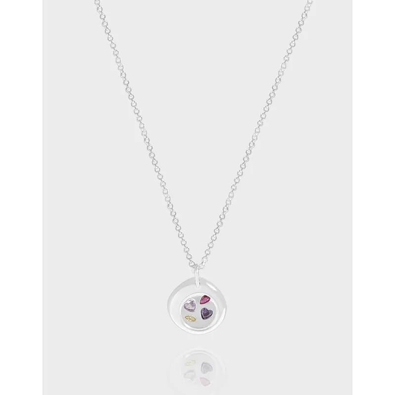 Polished circle pendant necklace with small colorful hearts hanging from a delicate chain.