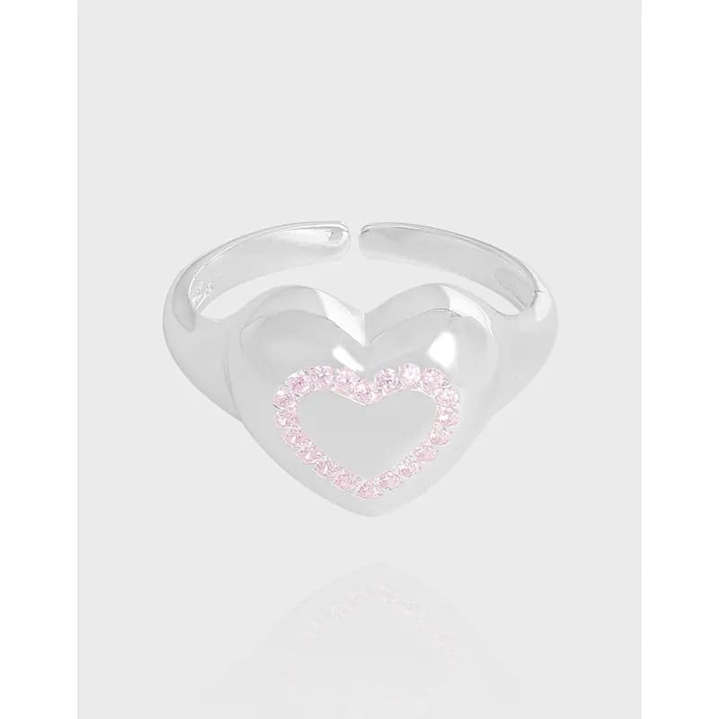 Polished sterling silver open heart ring with a pink pavé heart outline on a light background.