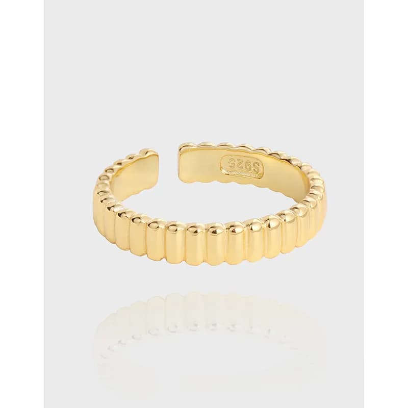 Close-up of a gold-tone ribbed ring with rounded beads and an open back.