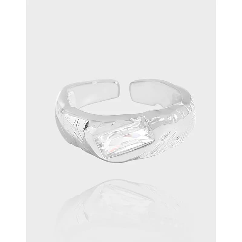 Polished sterling silver ring with a rectangular clear gemstone and engraved textured band