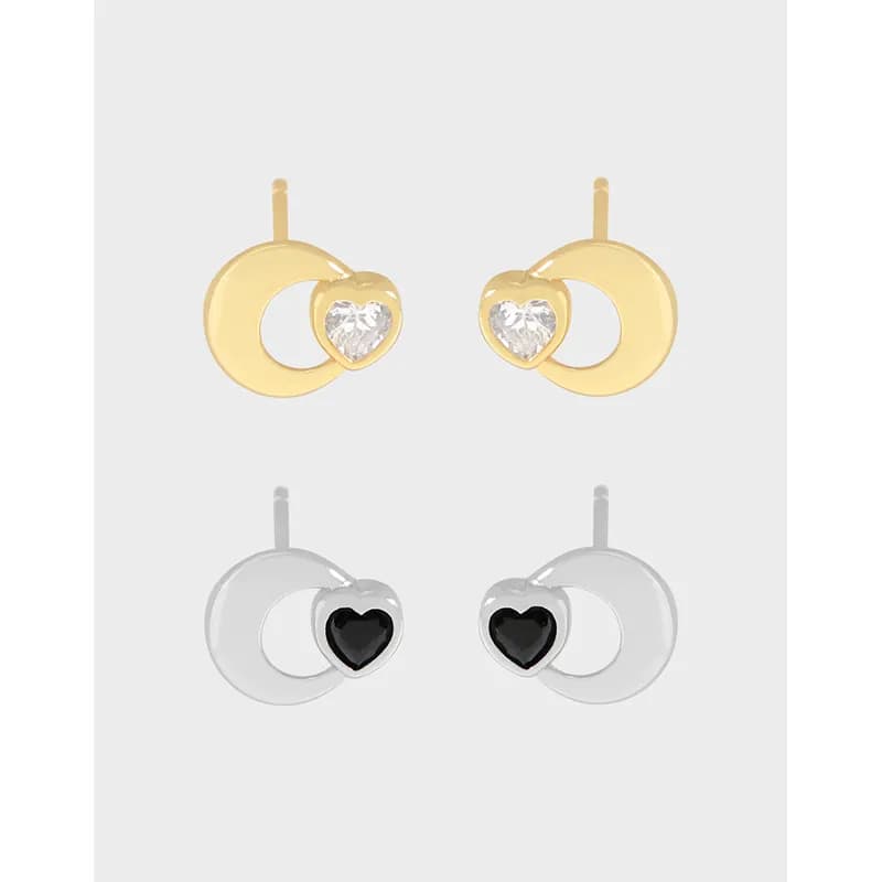 Polished silver earrings with a crescent hoop and heart charm displayed on a white background.