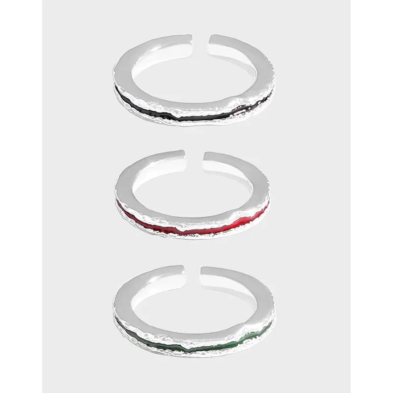 Three open-ended, textured sterling silver rings with thin colored enamel stripes in black, red, and green.