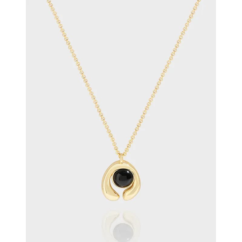 Gold-tone crescent pendant with a black round gemstone hanging on a delicate chain.