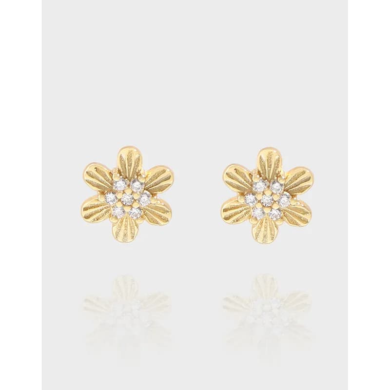 Polished sterling silver five-petal flower earrings with clear center stones on a light background.