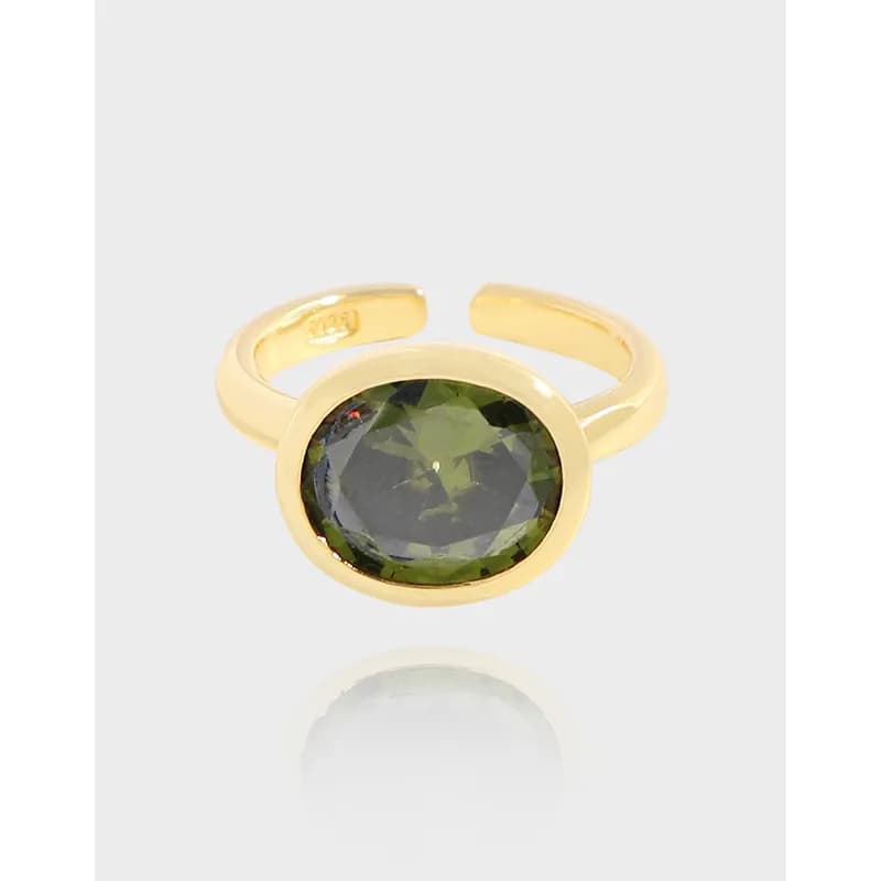 Open-style gold-tone ring with an oval faceted green stone set in a bezel on a polished band.