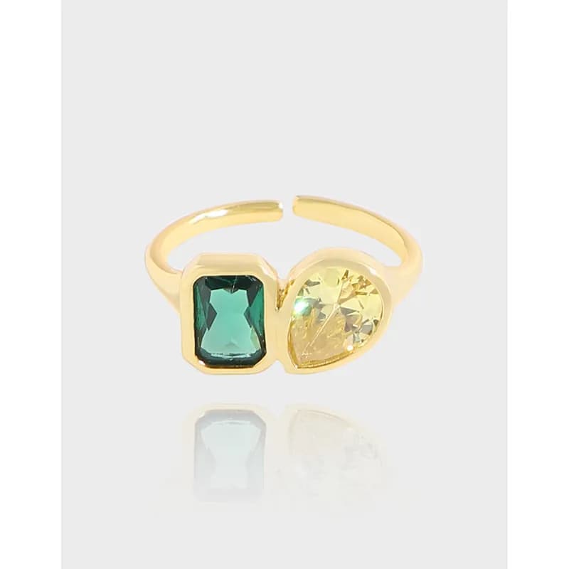 Polished sterling silver ring with two bezel-set stones: green square and yellow pear-cut, on an open split band.