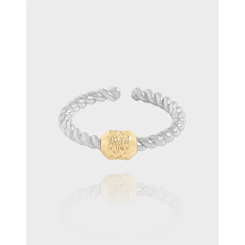 Open-ended silver ring with a twisted rope band and a gold hexagonal center accent on a light background.
