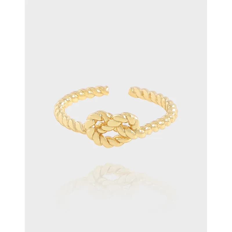 Polished sterling silver rope ring with a central knot design on a light background.