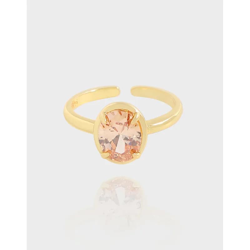 Polished sterling silver open-band ring with a round peach gemstone in a bezel setting.