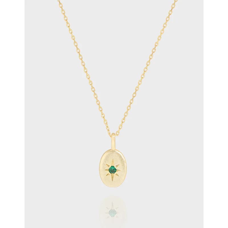 Delicate sterling silver necklace with an oval sunburst pendant and a green center stone on a fine chain.
