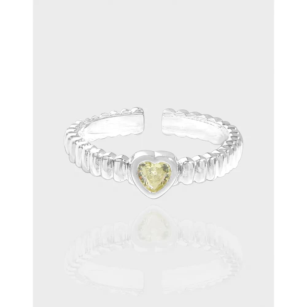 Polished sterling silver ring with a heart-shaped yellow gemstone centered on a segmented, scalloped band.