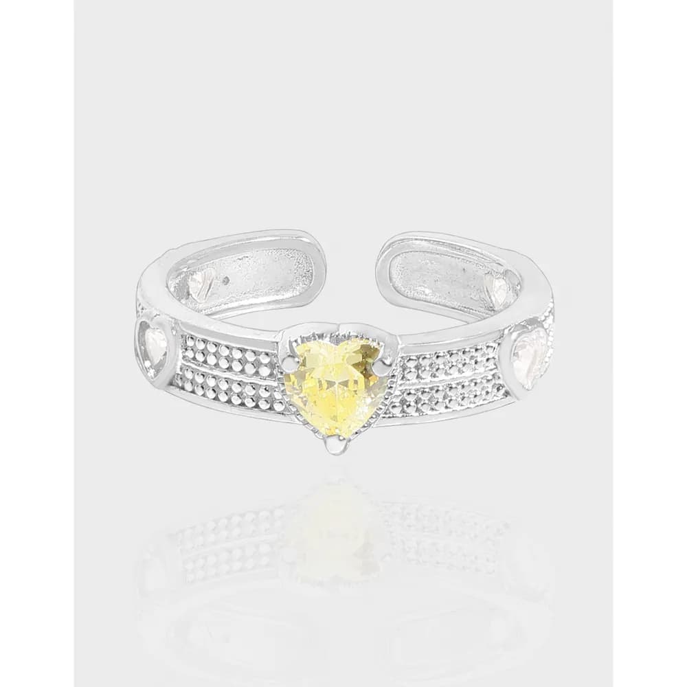 Sterling silver open-band ring with a yellow heart-shaped gemstone at the center and dotted band detailing.