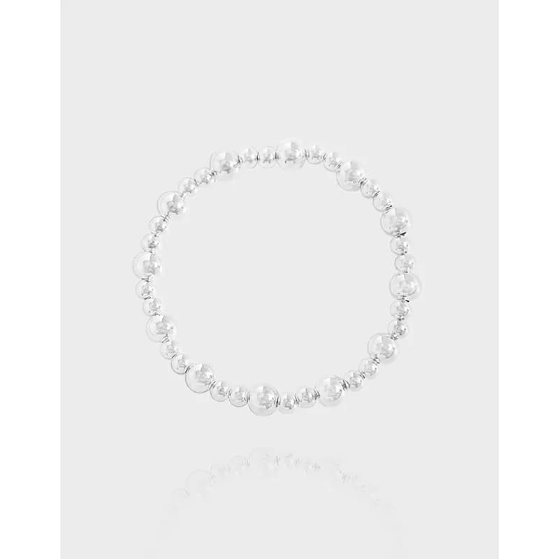 Polished sterling silver bead bracelet with uniform round beads on a pale background.