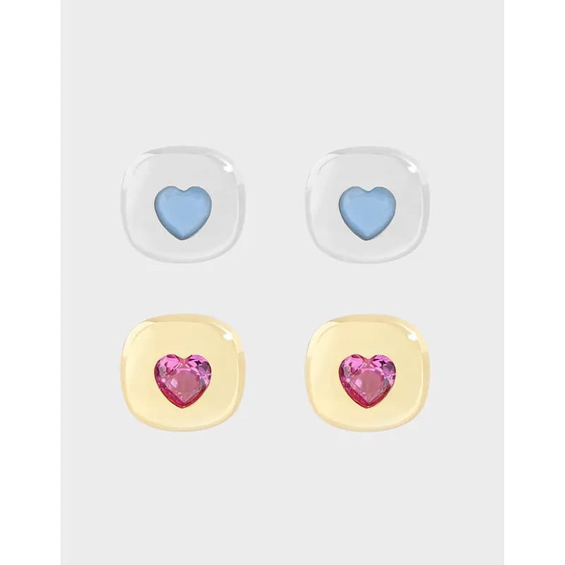 Close-up of two polished sterling silver stud earrings, each with a colored heart center