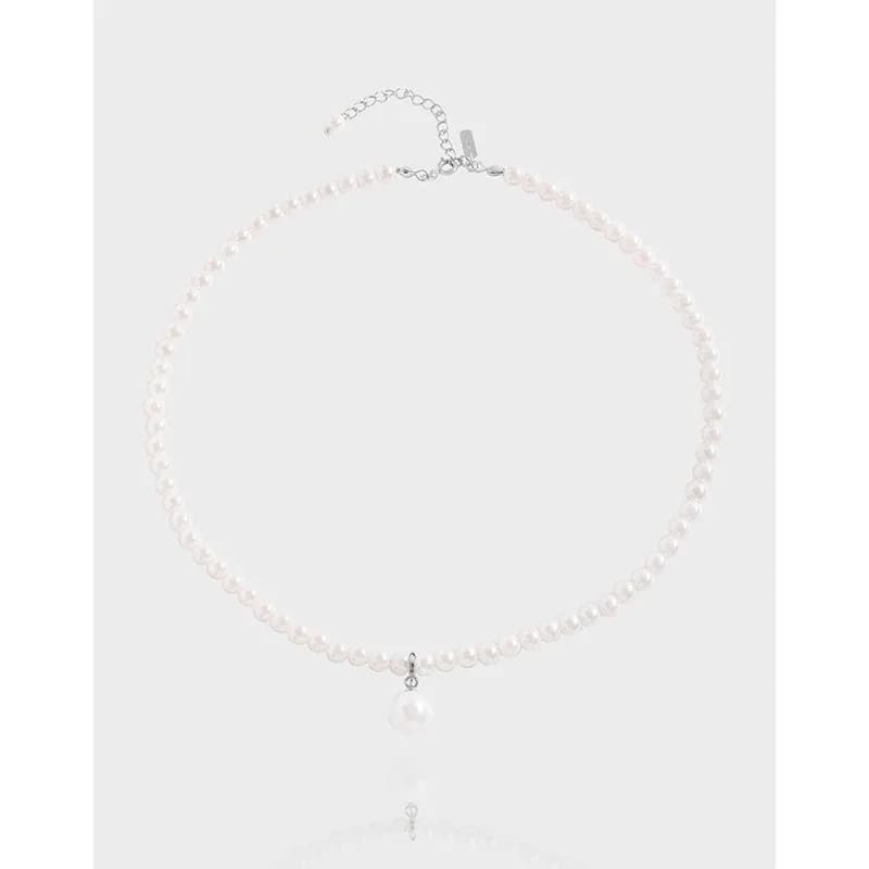 Polished sterling silver pearl necklace with a central drop pearl pendant on a light background.