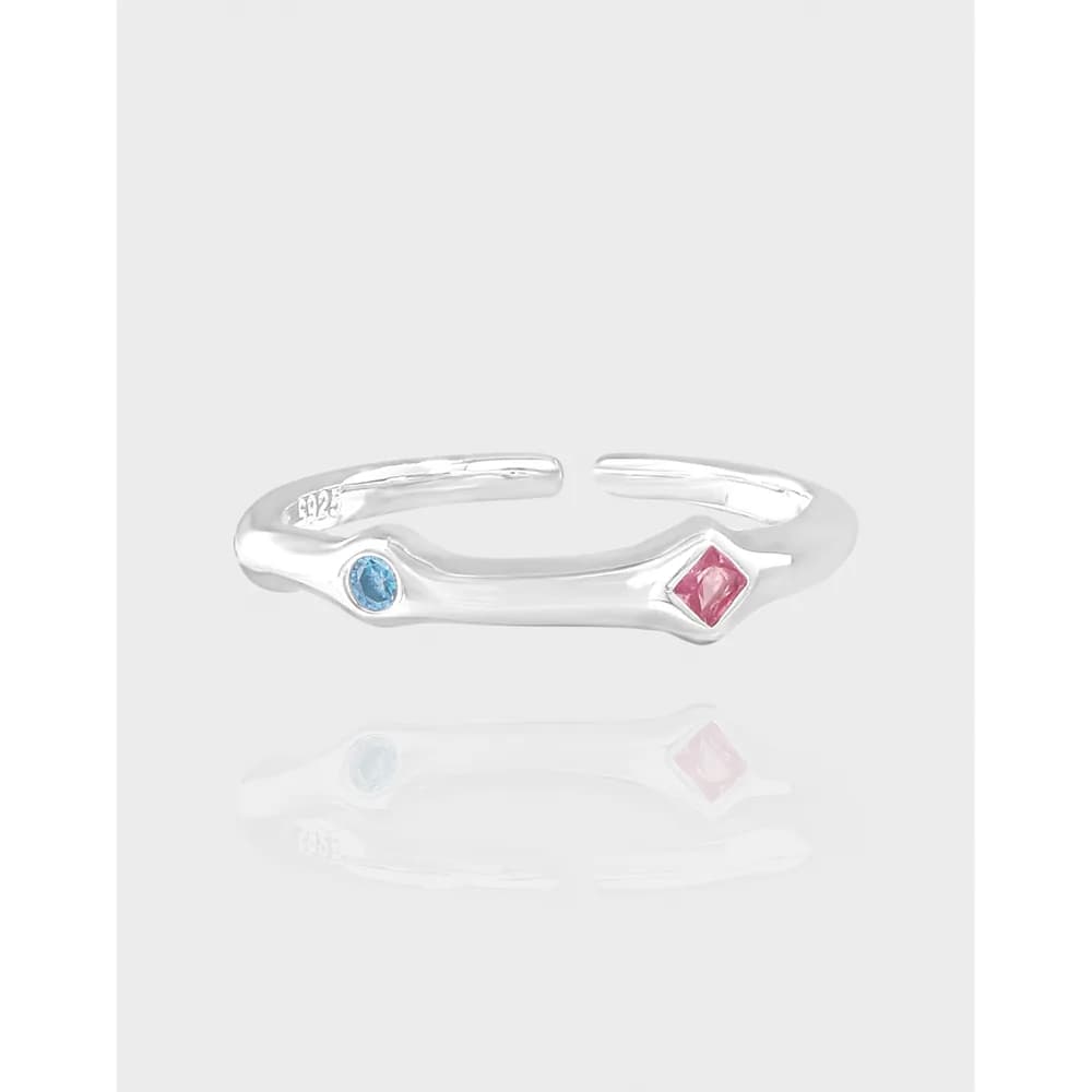 Polished sterling silver open ring with blue oval and pink square gemstones at opposite ends.