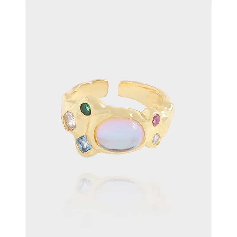 Polished sterling silver ring with a central opalescent cabochon and scattered colored stones in an organic setting.