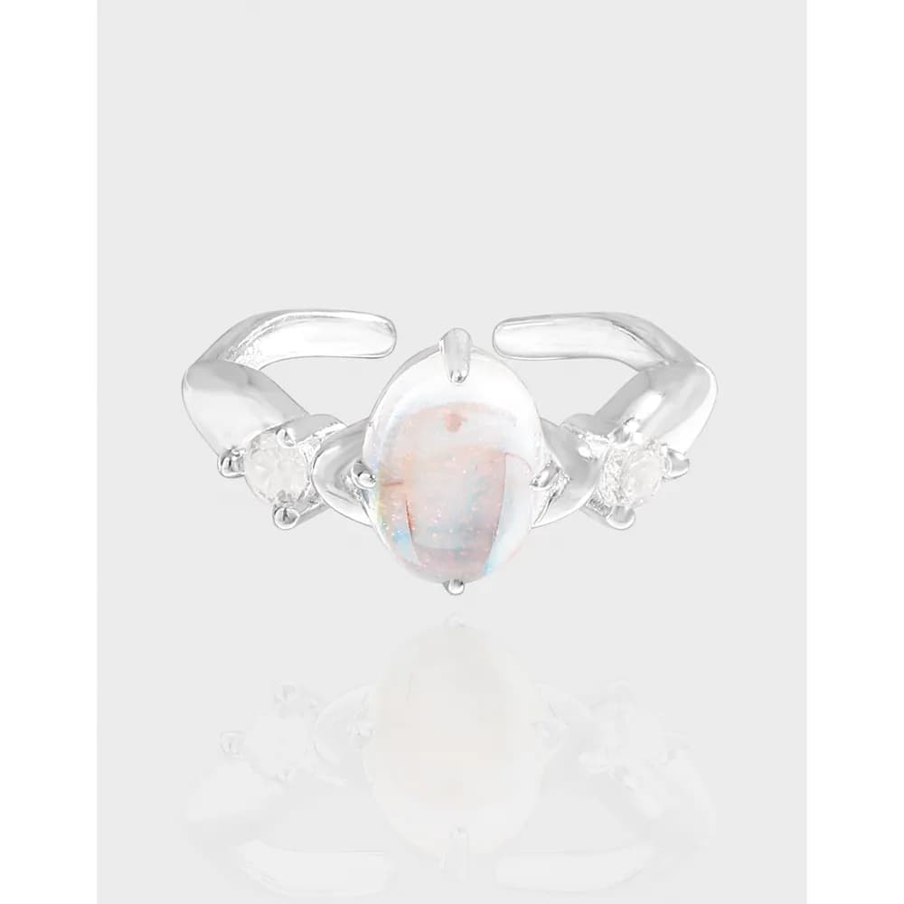 Polished sterling silver ring with a central oval opal and two side stones on a soft, light background.