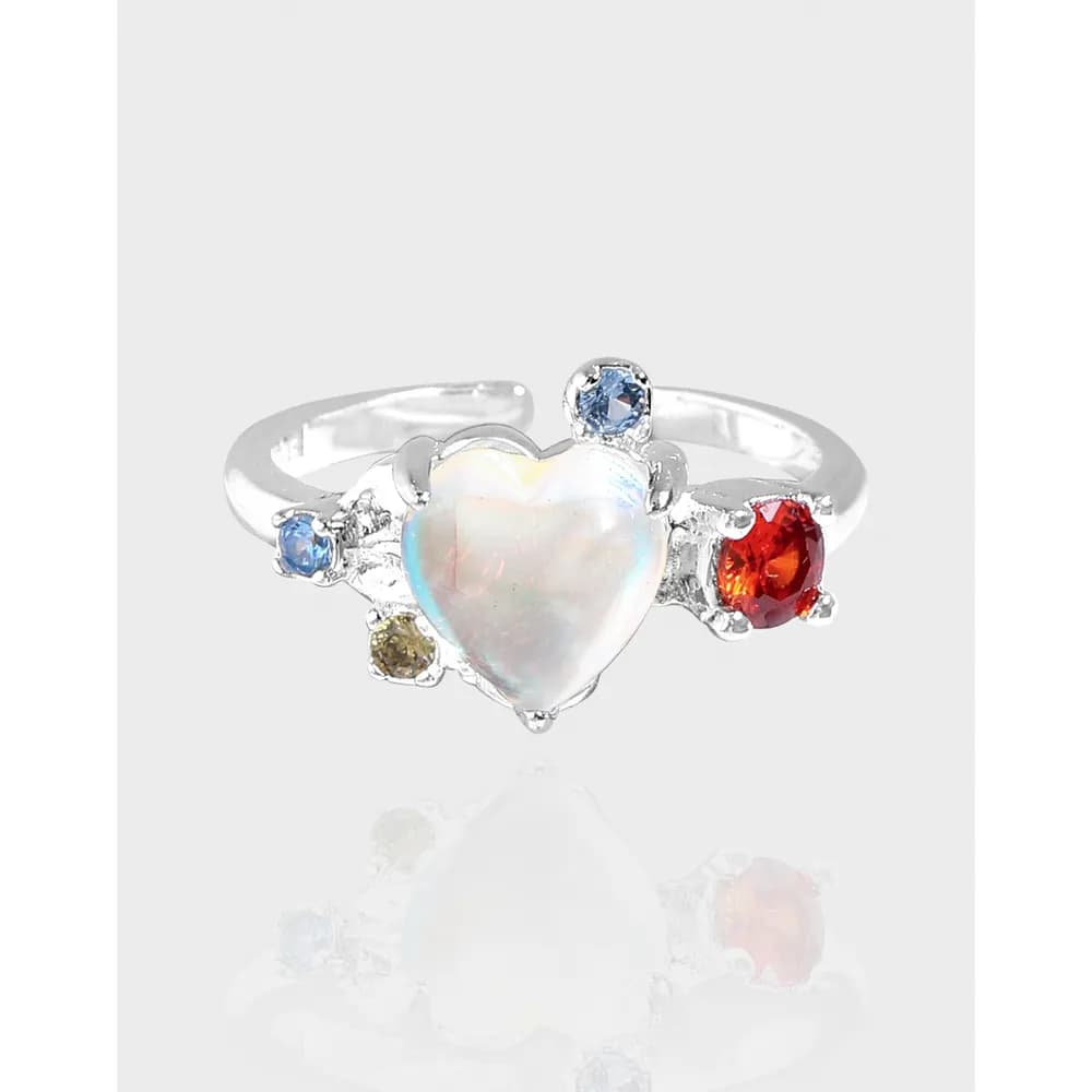 Sterling silver ring with a heart-shaped iridescent center stone and small blue, yellow, and red stones on a polished band.