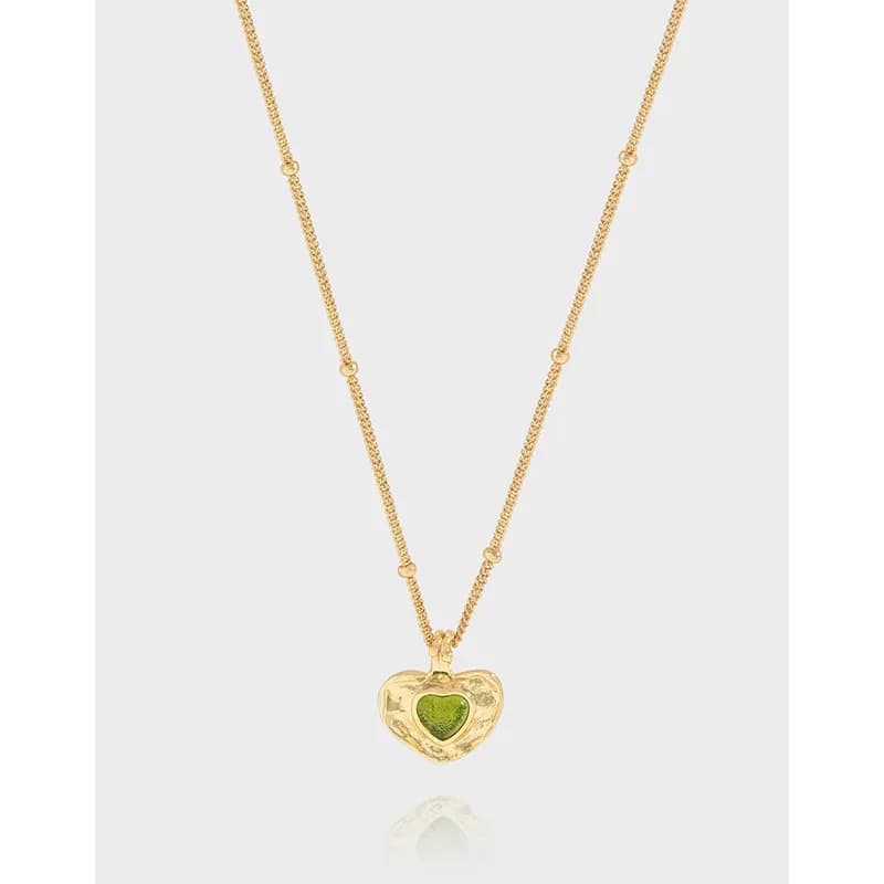 Sterling silver heart pendant necklace with a green center resting on a pale background.