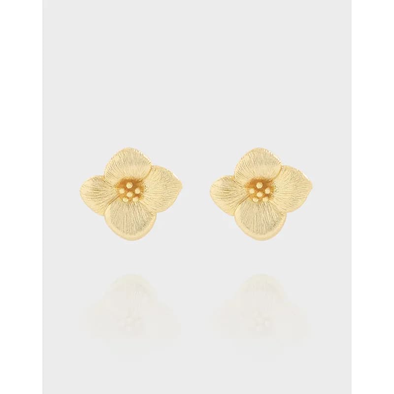 Polished sterling-silver flower stud earrings with four textured petals on a pale background.