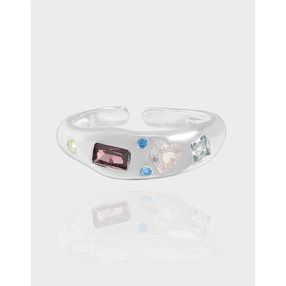 Polished sterling silver ring with mismatched colored gemstones arranged along the band.