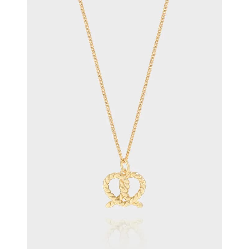 Polished silver necklace with interlocking rope-circle pendant on a thin chain.